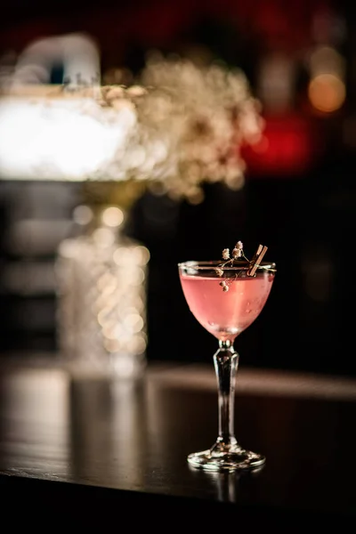 Beautiful glass with cocktail decorated with blooming twig stands on the bar. — Stock Photo, Image