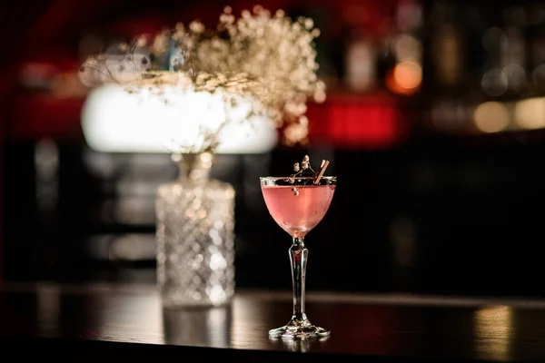Beautiful view of glass with cocktail decorated with blooming twig standing on the bar. — Stock Photo, Image
