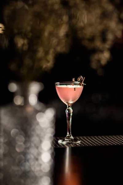 Beautiful crystal glass with cocktail decorated with blooming twig stands on the bar. — Stock Photo, Image