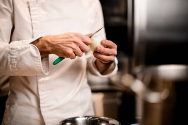 Soğanı nazikçe bıçakla soyan aşçının elleri.