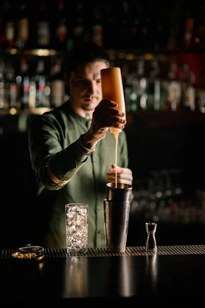 Man barman houdt fles van topping en voegt het toe aan glas shaker — Stockfoto