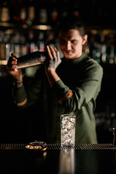 Vista de hermoso vidrio con hielo en el mostrador de bar. Barman borroso de fondo — Foto de Stock