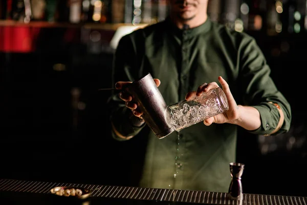Close-up op de handen van de man barman die stalen shaker cup en kristal glas houdt — Stockfoto