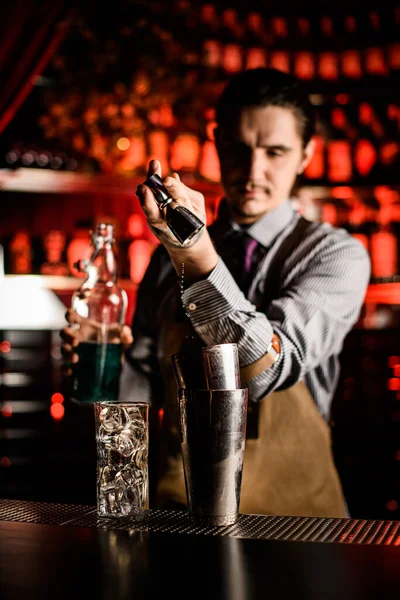 Professional bartender pouring drink from jigger into steel glass on bar counter — Stock Photo, Image