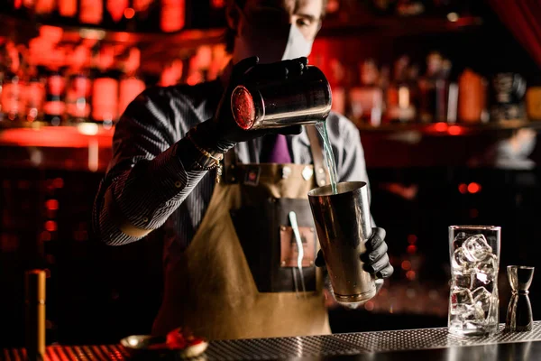 Mannelijke barman schenkt cocktail van de ene stalen shaker glas naar de andere — Stockfoto