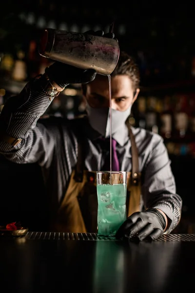 Joven camarero profesionalmente vierte cóctel de agitador de acero en la taza — Foto de Stock