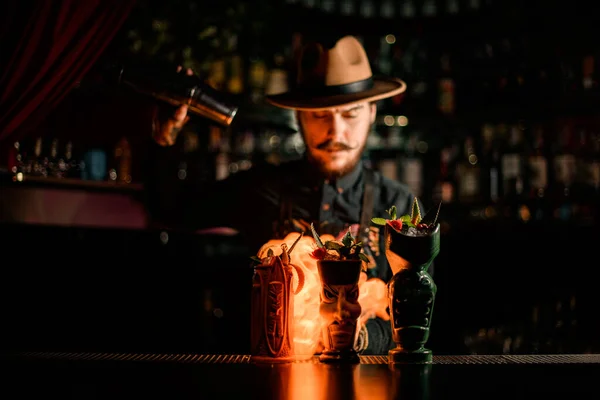 Vaso de lujo con soportes de cóctel en el bar y camarero prendiéndolo fuego al fondo —  Fotos de Stock