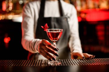 Çiçekle süslenmiş parlak kırmızı bir kokteyl ile güzel cam manzarayı kapat.