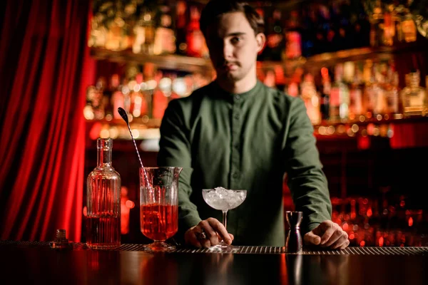 Hermosa vista de la botella de cristal con licor y taza de mezcla y vidrio en el mostrador de bar —  Fotos de Stock