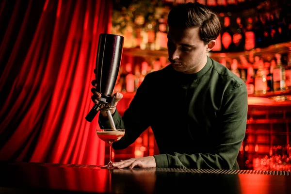 Barkeeper hält Werkzeug in der Hand und fügt Schaum zum Glas mit alkoholischem Cocktail hinzu — Stockfoto