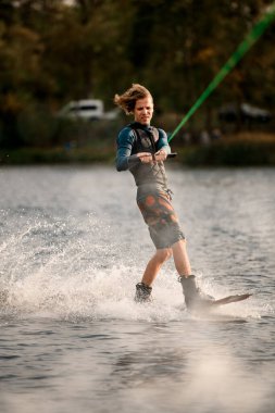 Wakeboard 'a binen enerjik adam nehre çok su sıçratıyor.