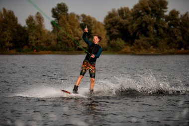 Mutlu genç adam kablolu TV 'yi tutuyor ve el hareketi yapıyor..