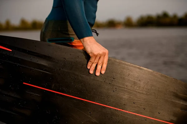 Close-up of mans hand holding black wakeboarding board. — Stok Foto