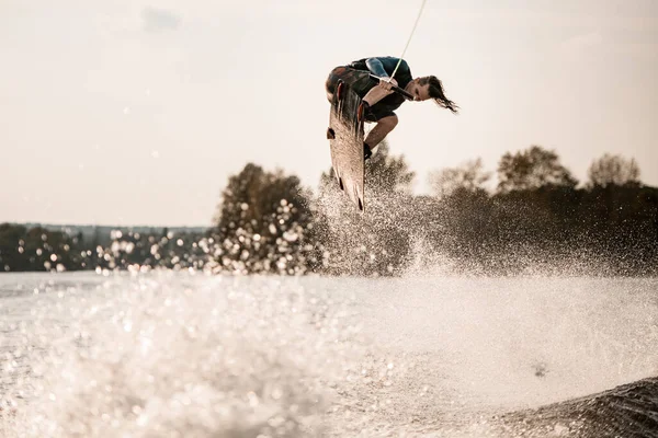 Young healthy athletic guy makes incredible jump on wakeboard — Stock Photo, Image