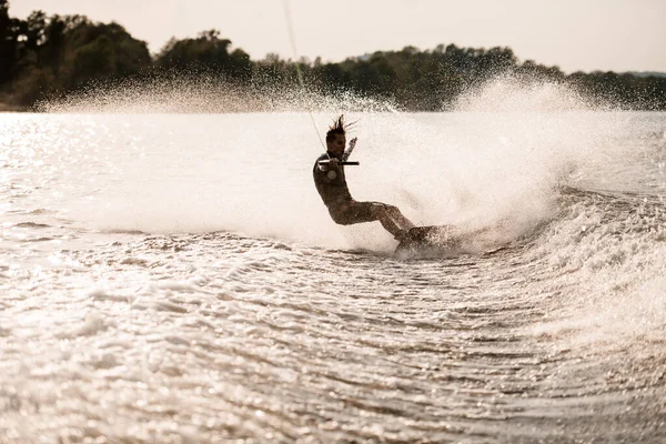 Vacker utsikt över stänkande flodvatten längs vilken sportig man rider på wakeboard — Stockfoto
