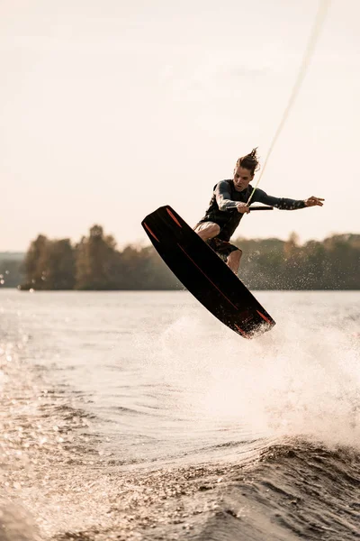 Young athletic man having fun on wakeboard on beautiful summer day. — Stock Photo, Image