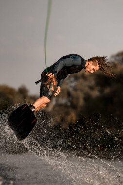 Atletik kaslı adam elinde iple Wakeboard 'a atlıyor..