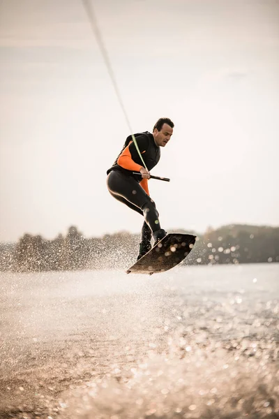 Man in wetsuit hebben plezier en springen op de golf op wakeboard. — Stockfoto