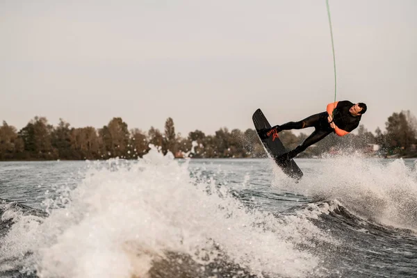 Zicht van de mens op wakeboard maken flip over spetterende rivier — Stockfoto