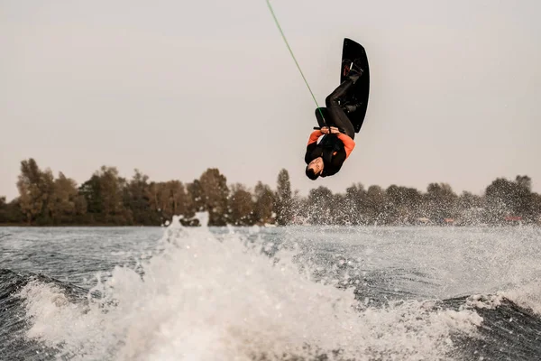 Aktiv idrottsman skickligt hoppar och gör vända över vattnet på wakeboard — Stockfoto