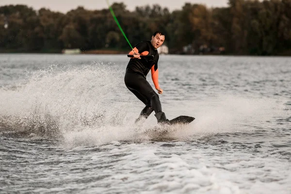 Verrast man houdt strak kabel in zijn handen en balanceert op golf op wakeboard — Stockfoto