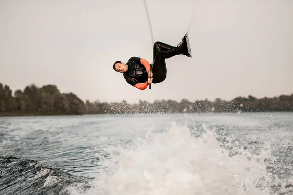 Actieve man springt en maakt flip over het water op wakeboard — Stockfoto