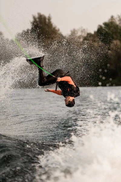 Actieve man springt en maakt flip over het water op wakeboard — Stockfoto