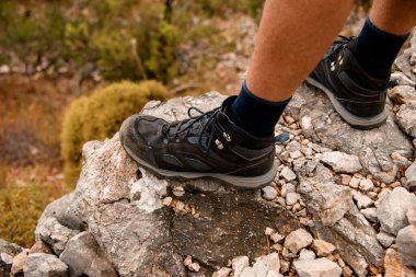 Uçurumun kenarında duran spor ayakkabılı adamın bacaklarına yakın plan.