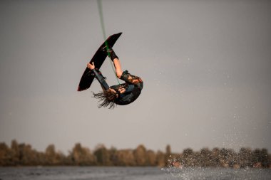 Enerjik adam yükseğe zıplar ve su üzerinde salto yapar.