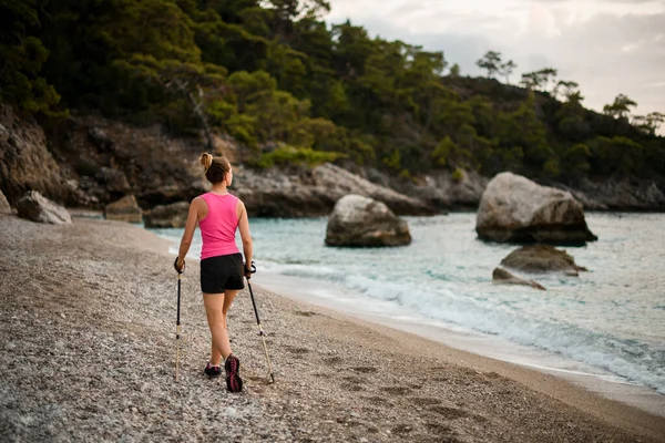 Bakifrån syn på ung kvinna promenader längs vilda stranden och bergen — Stockfoto