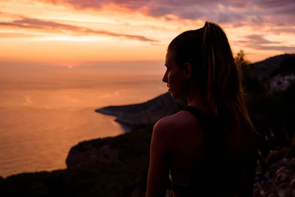 Bakre bild av vacker kvinna på bakgrund av berg, hav och solnedgång — Stockfoto