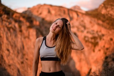 Güneş ışığıyla aydınlatılan dağın arka planında güzel genç bir kadının yakın görüntüsü