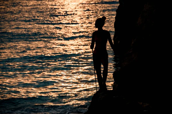 Vacker utsikt över kvinnan står nära klippan mot bakgrund av havet — Stockfoto