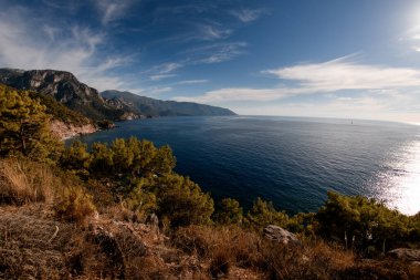Güzel mavi deniz, dağlar ve beyaz bulutlu gökyüzü.
