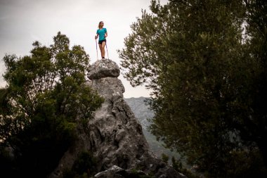 Taş dağın muhteşem manzarası. Üzerinde yürüyüş direkleri olan bir kadın.