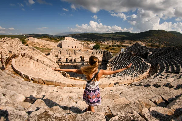 Hermosa mujer con las manos levantadas en las ruinas del anfiteatro de la antigua ciudad de Lycian Patara. — Foto de Stock