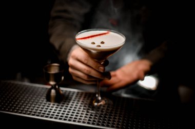 Kahve çekirdekleri ile süslenmiş espresso martini kokteyli ile erkeklerin elindeki cama yakından bakın.