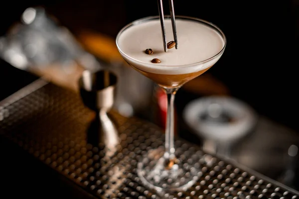 Fantastisk utsikt över glas med skummande espresso martini cocktail dekorerad med kaffebönor — Stockfoto