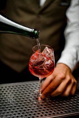 İçi buz dolu şeffaf bardaklar. Barmen şişeden su içiyor.