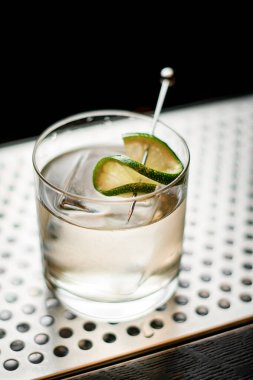 Kireç dilimleriyle süslenmiş buzla serinletici soğuk bir içecekle yakın plan cam.