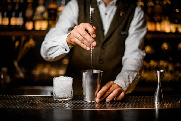 Vista sobre bartender segurando colher barra longa e mexendo coquetel no copo de mistura de aço — Fotografia de Stock