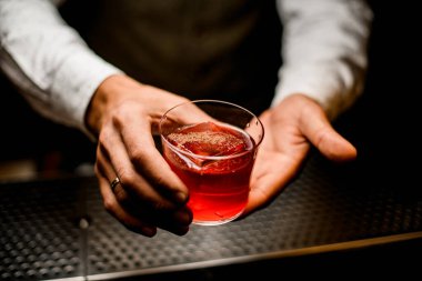 Parlak alkollü bardaklar ve buz küpleri erkek barmenlerin elinde.