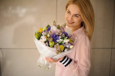 Gülümseyen bir kadının ellerinde bahar çiçeklerinden oluşan muhteşem bir buket