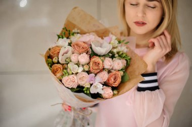 Kadının elindeki el işi kağıdına sarılı gül buketinin yakın plan görüntüsü