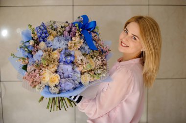 Genç, güzel, gülümseyen bir kadın. Farklı renkte, taze bahar çiçekleriyle dolu bir buket.