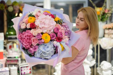 Çiçekçi kadının ellerinde büyük, muhteşem ortanca gülleri ve ranunculus çiçekleri.