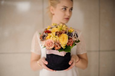 Çiçekçi kadının ellerinde yuvarlak kara kutuda inanılmaz bir çiçek aranjmanı.