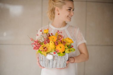 Hasır sepetin içinde, kadınların ellerinde parlak sarı çiçeklerle harika bir Paskalya çiçeği aranjmanı.