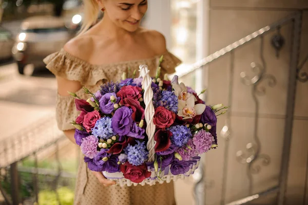 Vista magnífica do arranjo de flores em cesta de vime branco em mãos de mulher loira — Fotografia de Stock