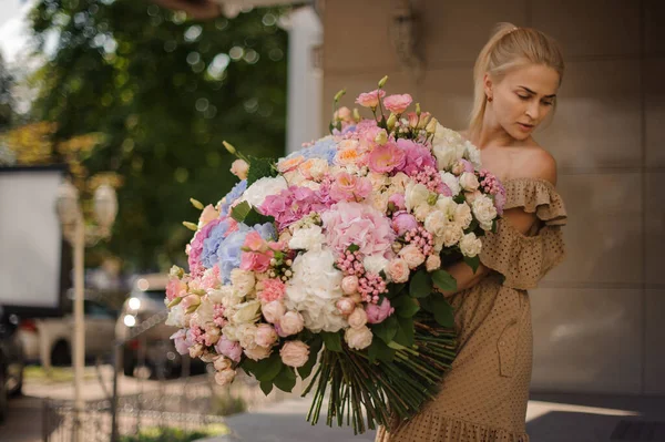 Blick auf junge blonde Frau mit riesigem Strauß unterschiedlicher Blumen in ihren Händen — Stockfoto